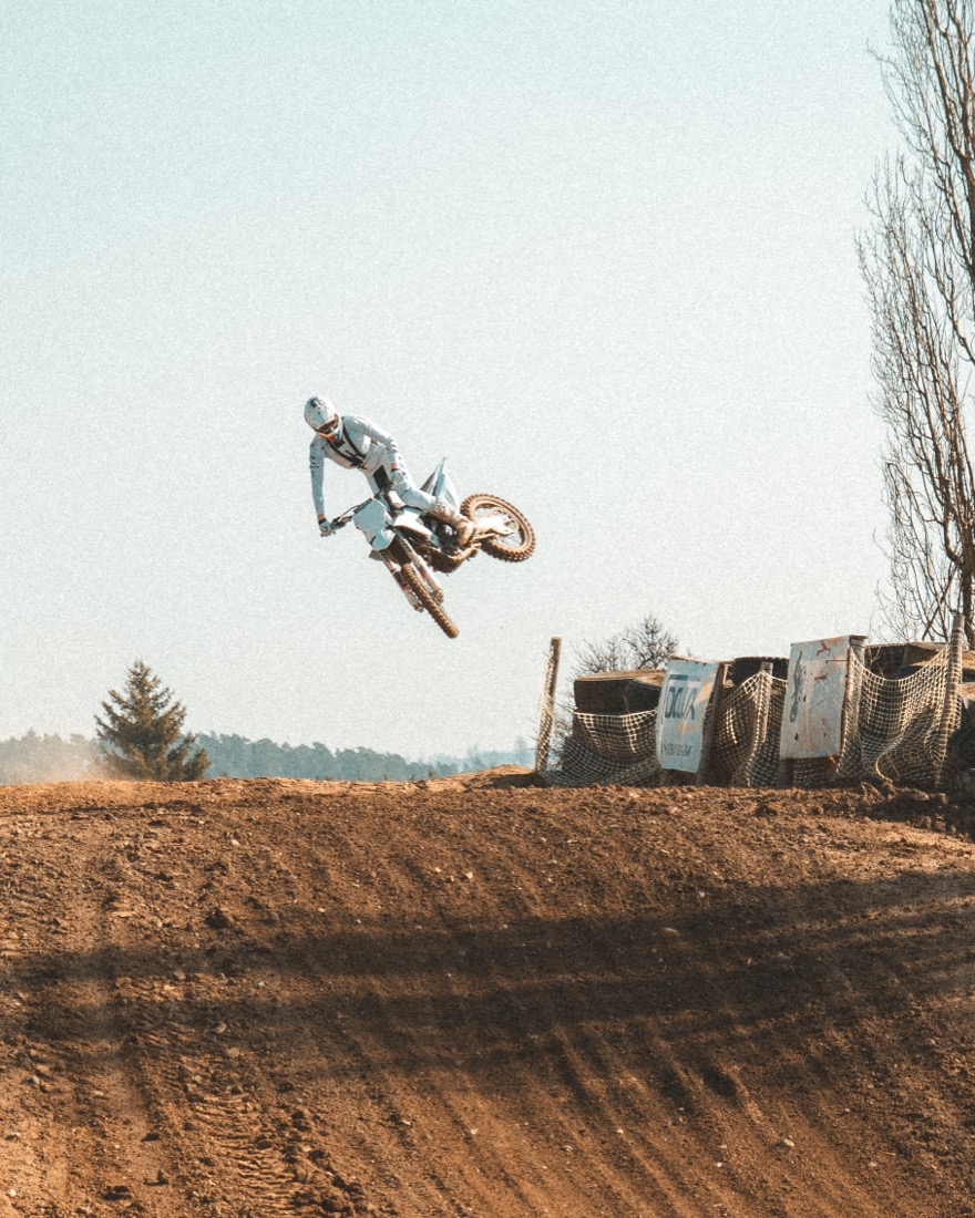 Motokrosový jezdec ve skoku nad překážkou