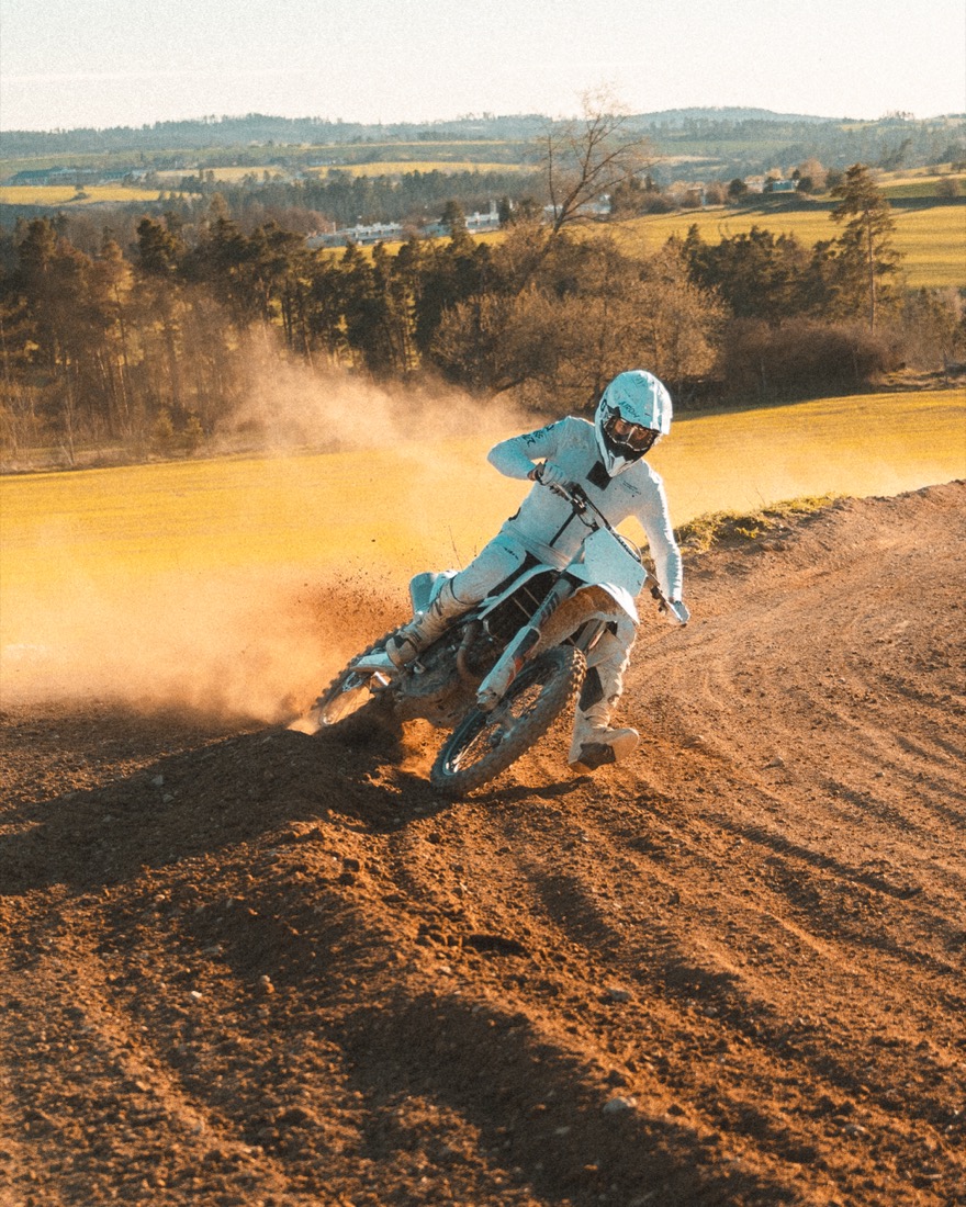 Motokrosový jezdec projíždí zatáčku ve smyku s prachem